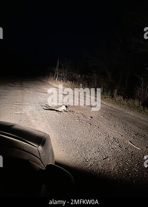 Proiettile russo MLRS Grad sulla strada alla luce dei fari per auto sul territorio dell'Ucraina. Risultato del bombardamento russo. Concetto di guerra, Russia Foto Stock