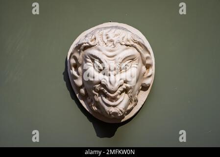 Brutto volto dell'uomo malvagio scolpito in un amuleto di pietra Foto Stock