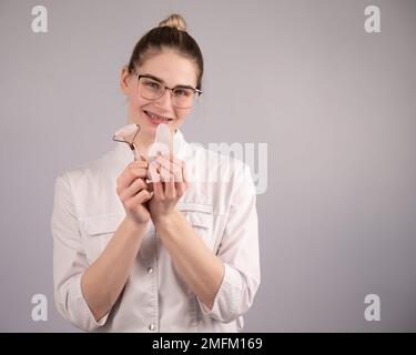 Medico estetista che tiene gouache raschietto e rullo. Foto Stock