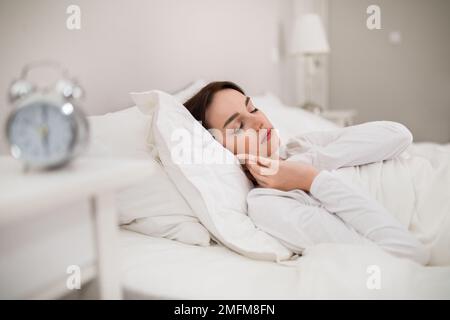 Bella donna in pigiama bianco che dorme a letto in camera da letto Foto Stock