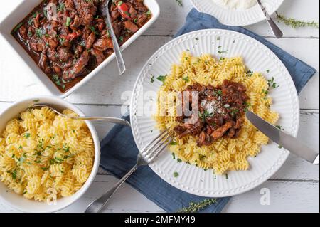 Ragù di pollo italiano con pasta al burro e parmigiano su fondo bianco. Giacitura piatta Foto Stock