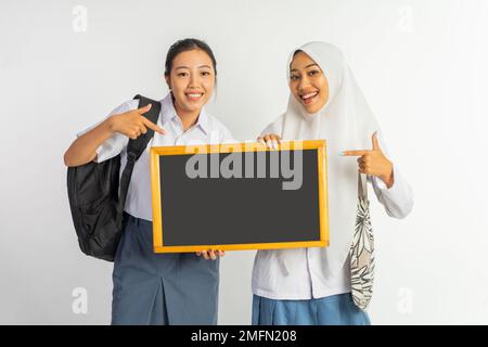 due ragazze sorridenti della scuola superiore professionale mentre trasportano le lavagne nere Foto Stock