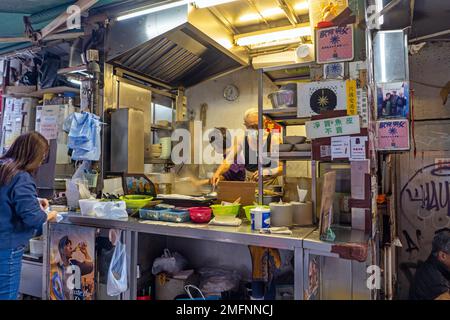 Hong Kong - 2022 dicembre - Stall Man cucina cibo dai Pai Dong Foto Stock