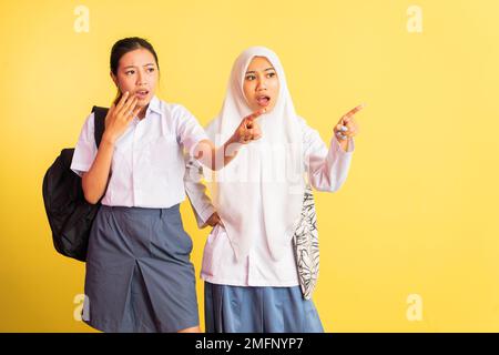 due ragazze scioccate della scuola superiore con il dito che indica Foto Stock