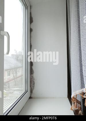 Muffa nera e fungo sulla parete vicino alla finestra. Il problema della ventilazione, dell'umidità, del freddo nell'appartamento Foto Stock
