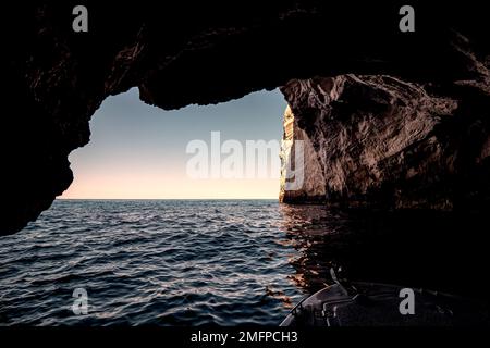 Vista del vasto orizzonte visto dall'interno di una grande grotta marina durante il tramonto Foto Stock