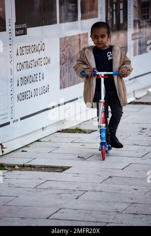 Bambino in scooter per le strade della città Foto Stock