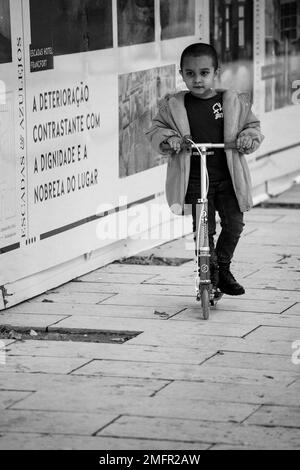 Bambino in scooter per le strade della città Foto Stock