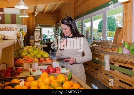 Il responsabile del negozio conta frutta e verdura in scatole di legno di un negozio di alimentari - Donna nel supermercato che fa l'inventario - concetti di piccole imprese Foto Stock