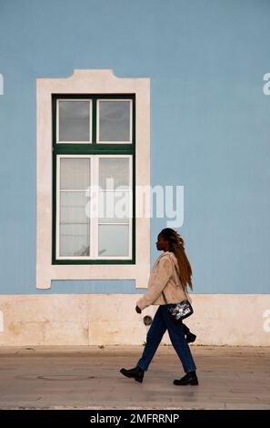 Una giovane donna cammina per le strade del centro di Lisbona Foto Stock