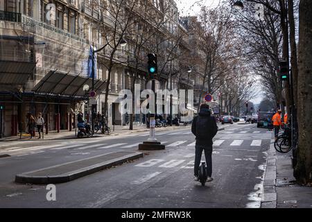 Un uomo guida una ruota lungo una strada parigina. Foto Stock