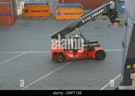 Impilatore di colore rosso con raccoglitore superiore per container carico e movimentazione intermodale nei terminal container in porto. Foto Stock