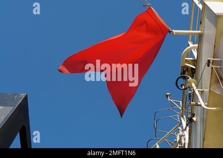 Bandiera rossa, bandiera marittima internazionale, battente sull'albero di navigazione della nave mercantile. Foto Stock