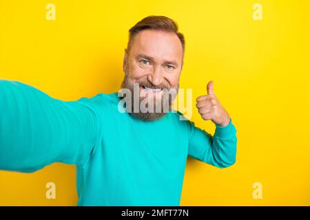 Ritratto fotografico di bel nonno video registrazione auto pollice su indossare abiti alla moda acquamarina isolato su sfondo giallo Foto Stock