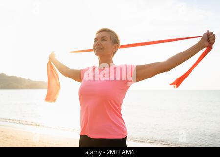 donna anziana con spiaggia di corda elastica Foto Stock