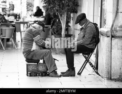 L'uomo anziano pulisce le scarpe per le strade Foto Stock