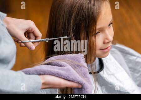 parrucchiere che taglia i capelli della bambina Foto Stock