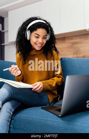 vista frontale ragazza giovane sorridente con cuffie durante la scuola online Foto Stock