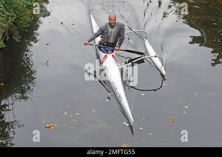 Veduta aerea canoista maschile pagaiando in italiano Allwave Vanguard Outrigger canoa lungo le acque ancora del fiume CAN nella città di Chelmsford Essex Inghilterra UK Foto Stock