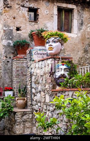 Cortile in uno dei vicoli della meta turistica di Taormina con teste di Moro, vasi decorativi in ceramica dipinti a mano e simbolo della Sicilia. Foto Stock