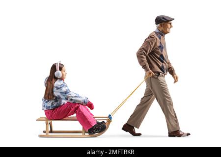 Profilo a tutta lunghezza di un uomo anziano che tira una ragazza con una slitta di legno isolata su sfondo bianco Foto Stock