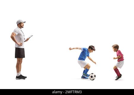 Allenatore a guardare due ragazzi che giocano a calcio isolato su sfondo bianco Foto Stock