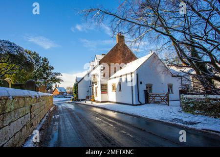 Vista della chiesa parrocchiale di St Mary coperta di neve ad Astbury vicino a Congleton Cheshire England della casa pubblica Egerton Arms nella neve d'inverno Foto Stock