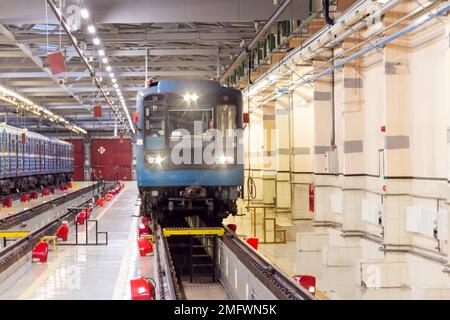 La metropolitana della locomotiva elettrica con i fari accesi arrivò al deposito. Treni passeggeri in arrivo al deposito elettrico Foto Stock