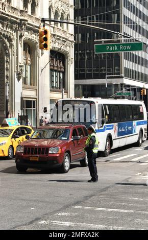 Un poliziotto del NYPD che si trova nel traffico intenso in un incrocio di Park Row Street, Lower Manhattan, New York City, NY, USA Foto Stock