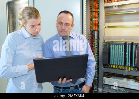 tecnici che discutono di un laptop nella sala server Foto Stock