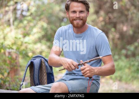 giovane turista tagliare legno in natura Foto Stock