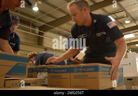 Personale della guardia costiera - forniture - 26-HK-84-65. CG personale con forniture -- CG NSF membri scatole di sollevamento in area di stoccaggio, 050901l. Uragano Katrina Foto Stock