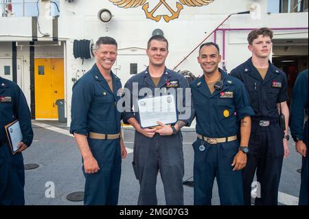 MARE DELLE FILIPPINE (20 agosto 2022) – Capitan Jeffrey Feinberg, comandante della USNS Mercy (T-AH 19), a sinistra, E il capo maggiore del comando Manuel Valle, a destra, premia il compagno machinista 2nd Classe Nathan Rich, centro, marinaio del mese di luglio a bordo della nave militare dell'ospedale Sealift Command USNS Mercy (T-AH 19) in riconoscimento degli sforzi di Rich durante il Pacific Partnership 2022. Ora nel suo 17th° anno, Pacific Partnership è la più grande missione multinazionale annuale di assistenza umanitaria e di preparazione alle catastrofi condotta nell'Indo-Pacifico. Foto Stock