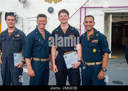 MARE DELLE FILIPPINE (20 agosto 2022) – Capitan Jeffrey Feinberg, comandante della USNS Mercy (T-AH 19), a sinistra, E il capo maggiore del comando Manuel Valle, a destra, premia Information Systems Technician 3rd Class Nicholas Marshall, Center, Sailor del mese di luglio a bordo della nave militare dell'ospedale Sealift Command USNS Mercy (T-AH 19) in riconoscimento degli sforzi di Nicholas durante Pacific Partnership 2022. Ora nel suo 17th° anno, Pacific Partnership è la più grande missione multinazionale annuale di assistenza umanitaria e di preparazione alle catastrofi condotta nell'Indo-Pacifico. Foto Stock