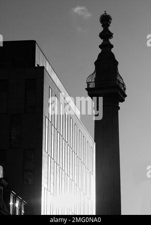 Monocromatico, bianco e nero del Monumento in Silhouette retroilluminato dal Sole contrastato con Un moderno blocco di uffici, City of London UK Foto Stock