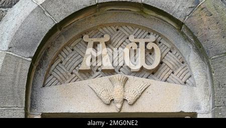 Alpha e Omega con una colomba sotto in cima ad una porta di una chiesa cattolica romana Foto Stock