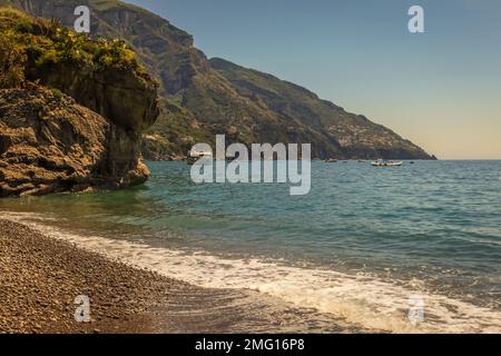 Positano spiaggia e scogliere a Positano durante le giornate estive di sole, costiera amalfitana, Italia Foto Stock