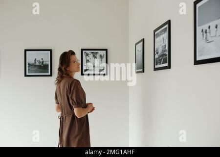 Donna matura che guarda foto in bianco e nero in museo Foto Stock