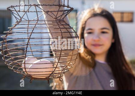 La bambina tiene una tazza di uovo di filo arrugginito. Stile country. Messa a fuoco selettiva Foto Stock