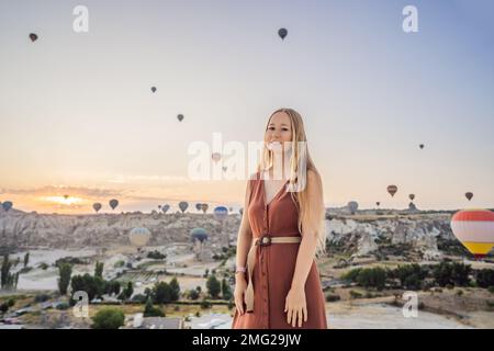 Donna turistica che guarda mongolfiere in Cappadocia, Turchia. Buon viaggio in Turchia concetto. Donna in cima a una montagna che gode di una vista meravigliosa Foto Stock