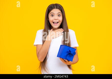 Bambino con confezione regalo su sfondo isolato studio. Regali per il compleanno dei bambini. Adolescente eccitato, contento stupito e overjoyed emozioni. Foto Stock