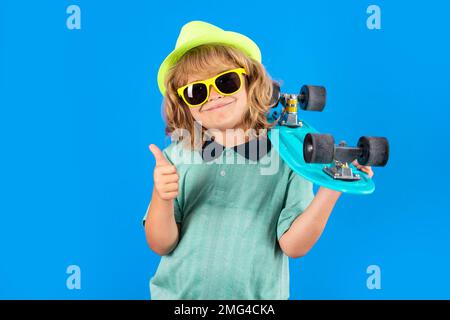 Studio ritratto di elegante carino bambino ragazzo con skateboard isolato su sfondo blu. Skater per bambini. Ragazzo di moda. Piccolo bambino alla moda Foto Stock