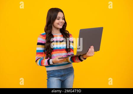 Studentessa adolescente scolastica con laptop su sfondo isolato. Webinar online, lezione di elearning, pc. Felice adolescente, positivo e sorridente Foto Stock