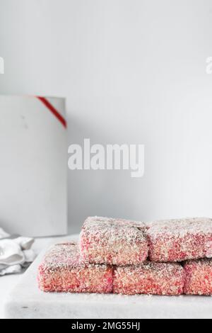 Lamponi rosa su vassoio di marmo, lamponi australiani, torta ricoperta di noci di cocco essiccate Foto Stock