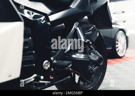 Inquadratura ravvicinata a basso angolo della ruota di una moto nera. Salone auto. Garage interno. Scatto orizzontale in interni. Foto di alta qualità Foto Stock