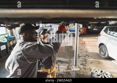 Immagine media di due meccanici che eseguono la sostituzione della frizione in un'officina di riparazione. Foto di alta qualità Foto Stock