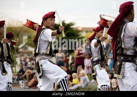 I batteristi SHIME-daiko con Jaagaru EISA Group si esibiscono in una marcia EISA su Camp Foster, Okinawa, Giappone, 21 agosto 2022. Originario di Okinawa, l'EISA iniziò come una danza tradizionale eseguita dai monaci buddisti giapponesi per onorare gli spiriti dei loro antenati. Da allora, EISA si è evoluta in una forma di intrattenimento moderno comunemente eseguito durante il Festival di Obon nei mesi estivi. Foto Stock