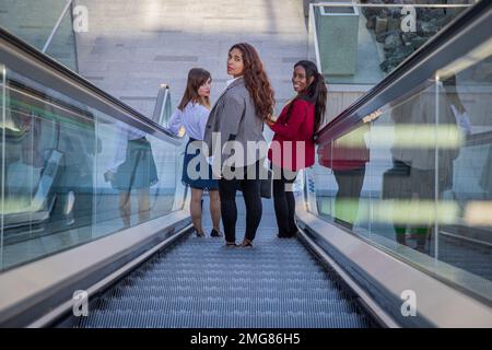 Tre donne d'affari sulle scale mobili nella costruzione di affari sul loro senso lavorare Foto Stock