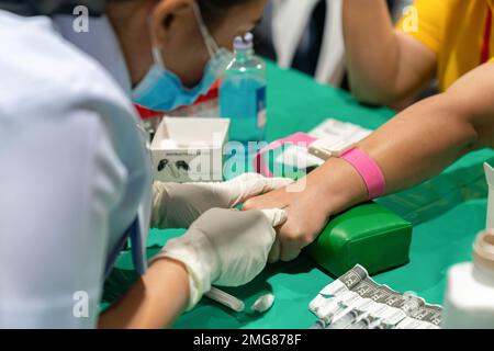 Un infermiere sta usando un ago per prelevare il sangue per un esame al controllo sanitario annuale. Foto Stock