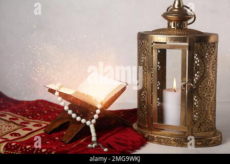 Lanterna musulmana con libro di Corano, tappeto di preghiera e tasbih su sfondo chiaro Foto Stock